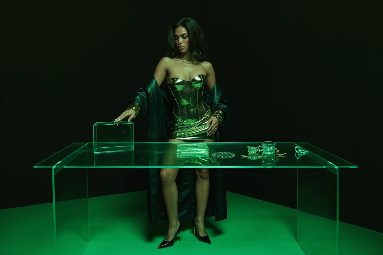 Seven Yuno arranges glass objects at a glass desk under green light.