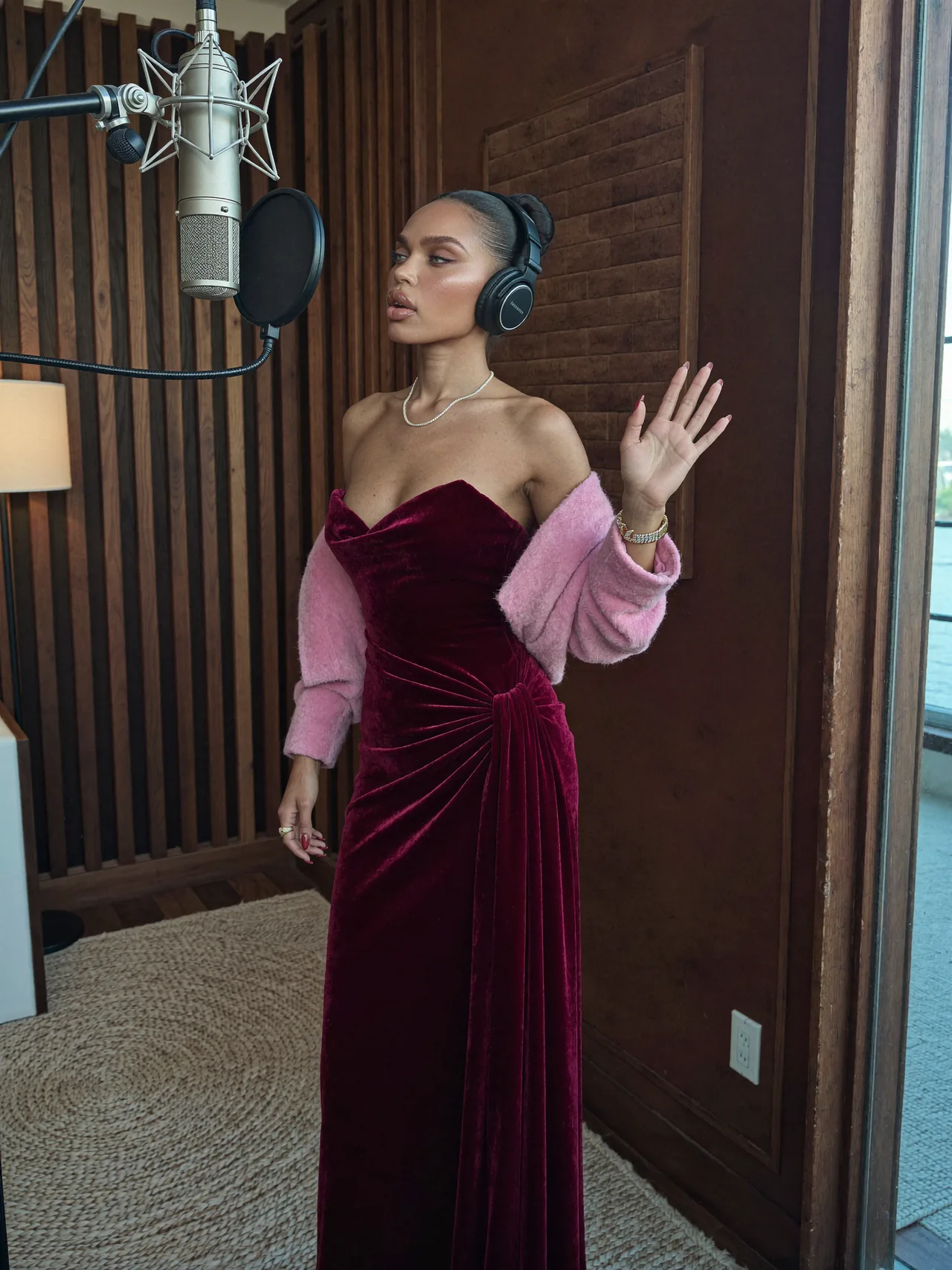 Seven Yuno sings in a vocal booth in a burgundy velvet gown.