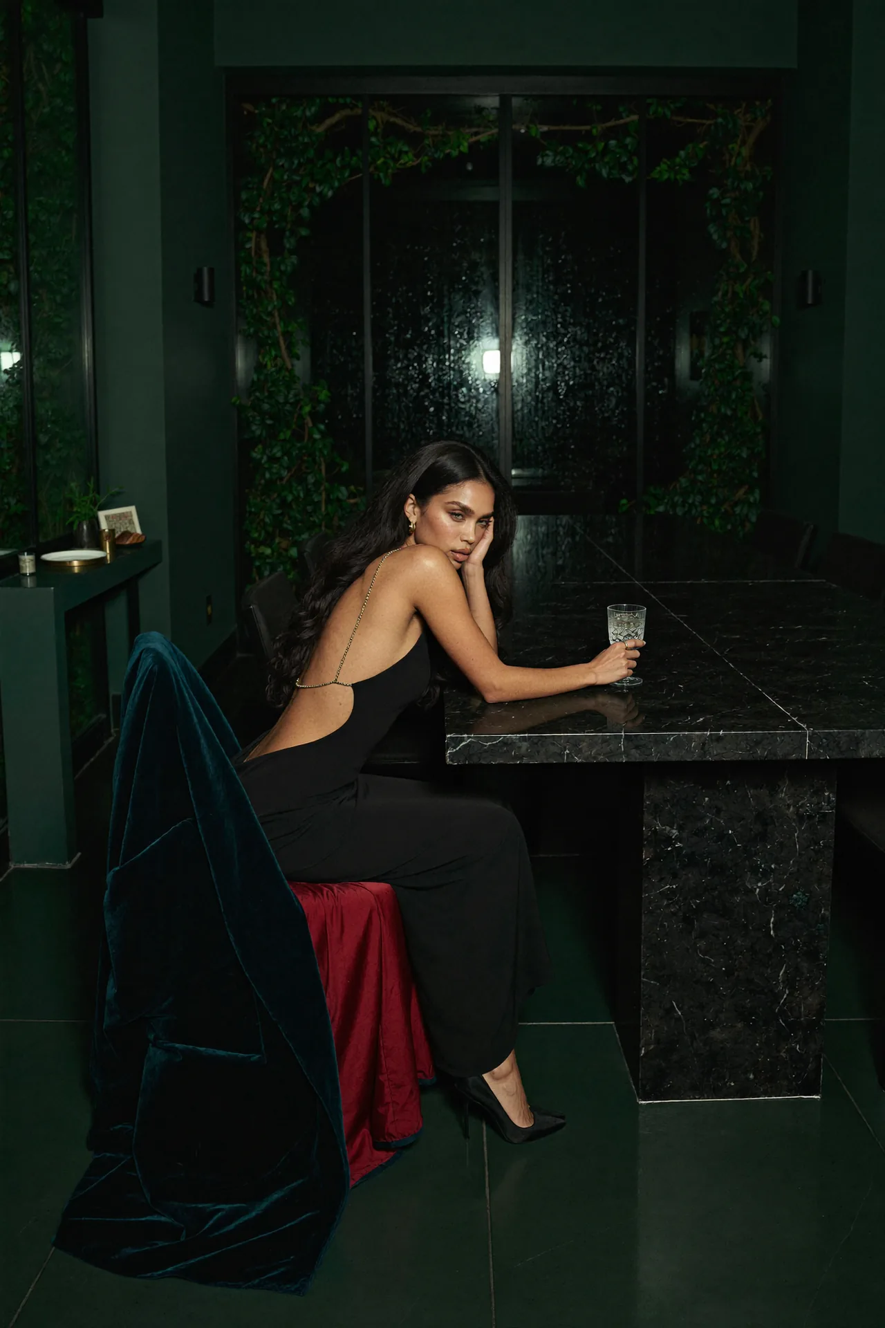 Seven Yuno sits at a marble table in a dark green salon.